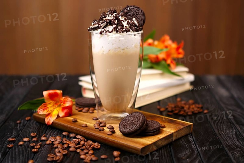 Glass with coffee cocktail with whipped cream and cookie decorated with coffee beans and flowers