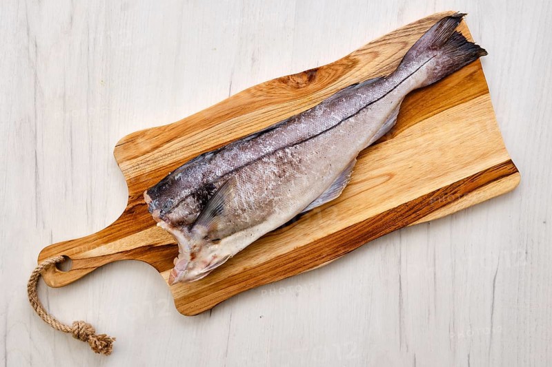 Top view of raw fresh haddock carcass on wooden cutting board