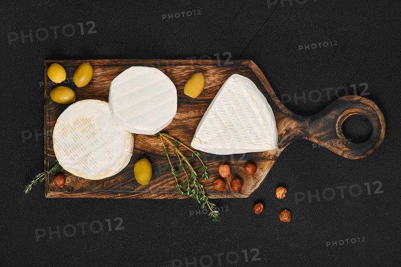Top view of cheese platter. Assortment of brie and camembert cheese on wooden cutting board