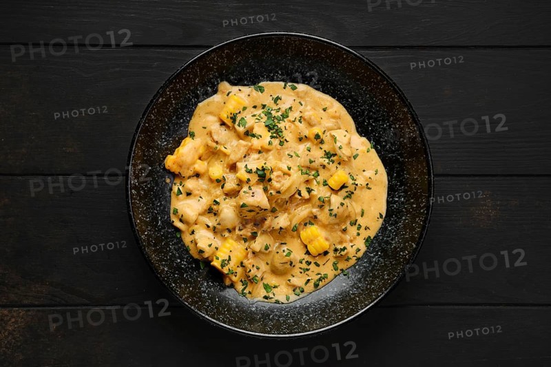 Chicken meat with corn and fried onion covered with creamy sauce on a plate
