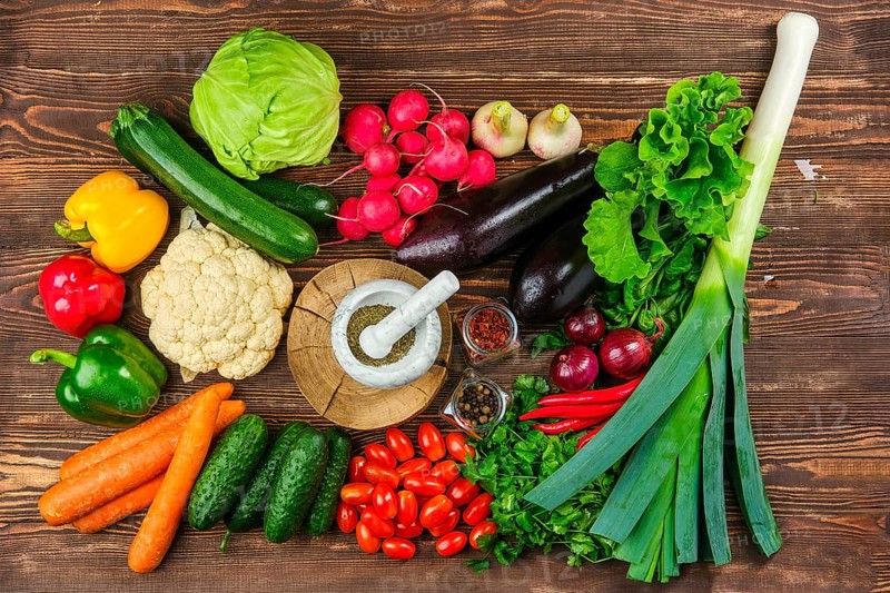 Top view of various fresh vegetables and herbs on dark wooden background