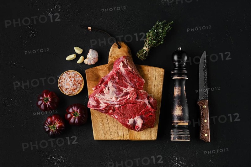 Raw beef top round roast with spices on dark background