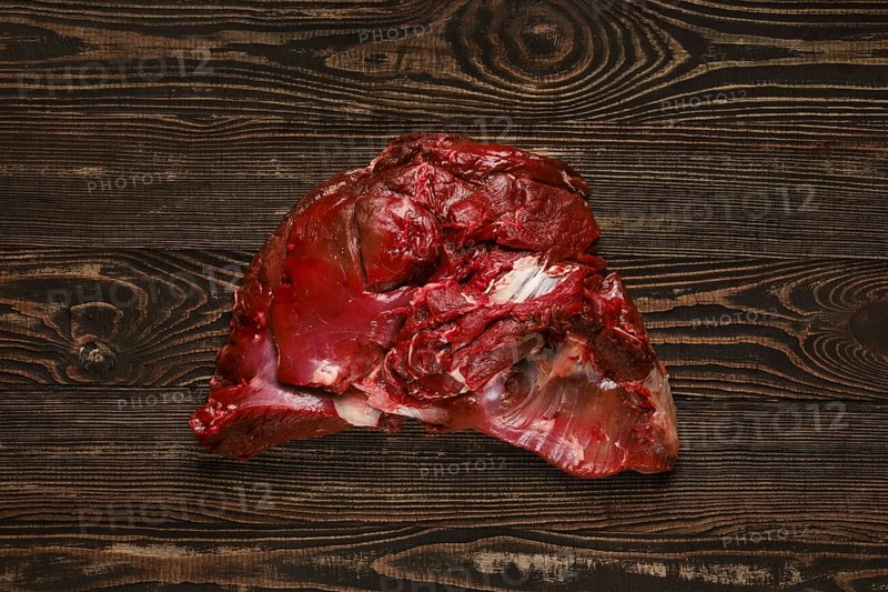 Overhead view of raw deer boneless ham over wooden background