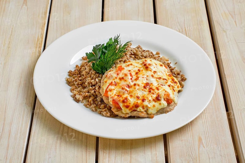 Chopped pork meat baked with cheese and tomato served with buckwheat porridge