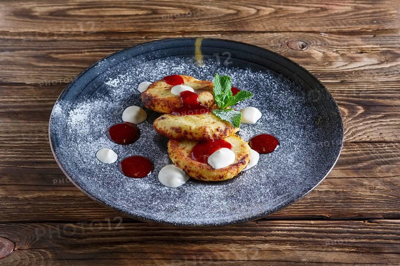 Cheese pancakes served with sour cream and strawberry jam