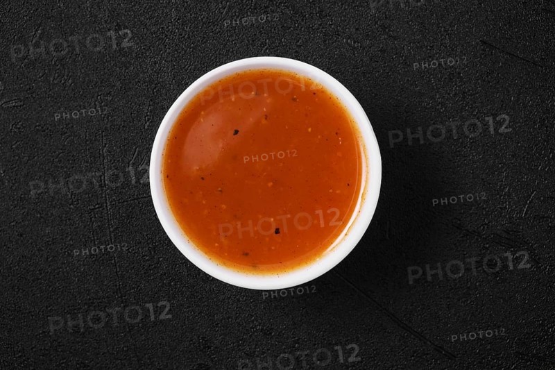 Overhead view of small bowl with spicy orange sauce for poultry