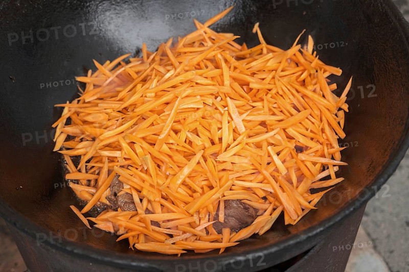 Meat orange carrot and onions in cauldron. The making of pilaf