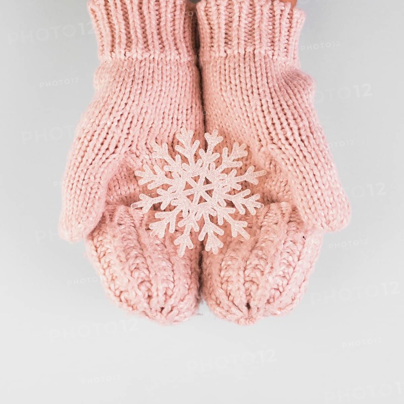Person hands in mittens with paper snowflake