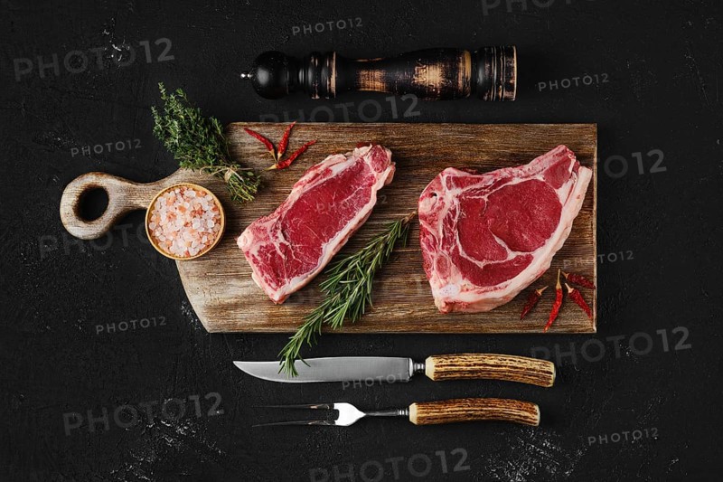 Raw strip steak bone in and boneless on dark background