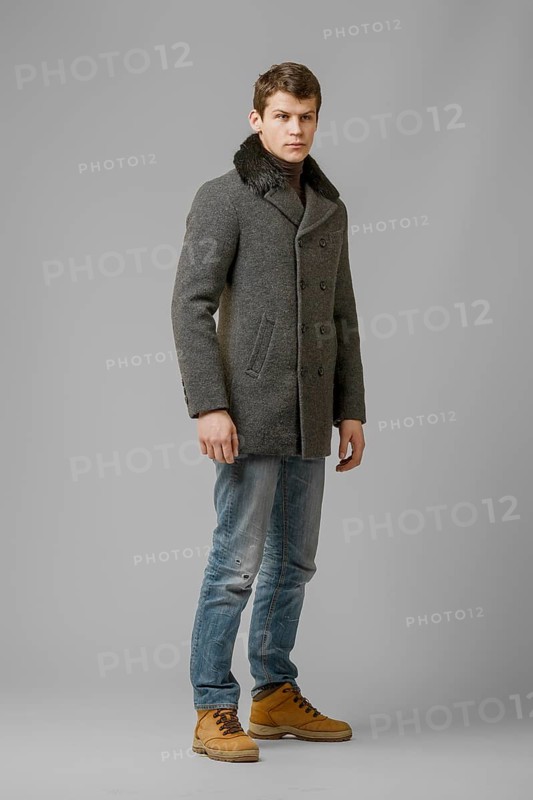 Full length portrait of handsome man in warm woolen coat posing in studio