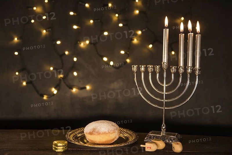 Gelt dreidels lying near doughnut menorah