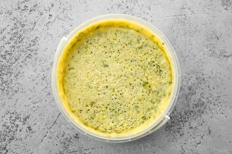 Top view of homemade soft cheese with herbs in plastic bowl