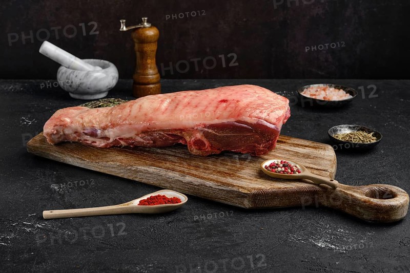 Raw half of turkey breast with bone and skin on dark background