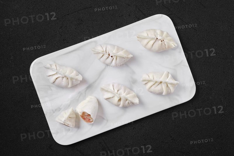Top view of frozen dumplings stuffed with liver and provencal herbs on marble serving plate