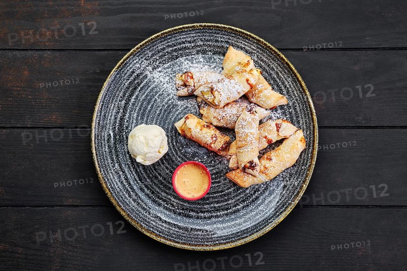 Top view of baked pear wrapped in pastry with cinnamon served with ice cream