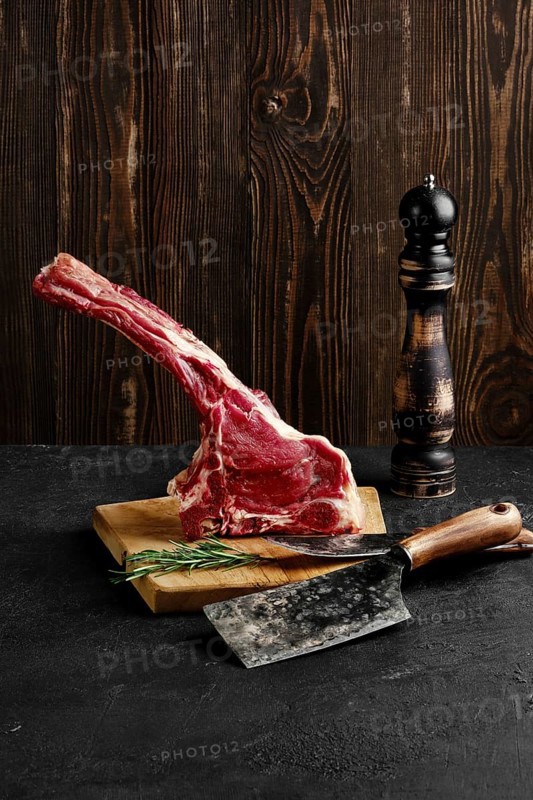 Raw prime ribeye steak on wooden cutting board