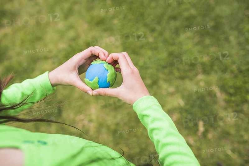 Heart shape hands surrounds colorful plasticine planet