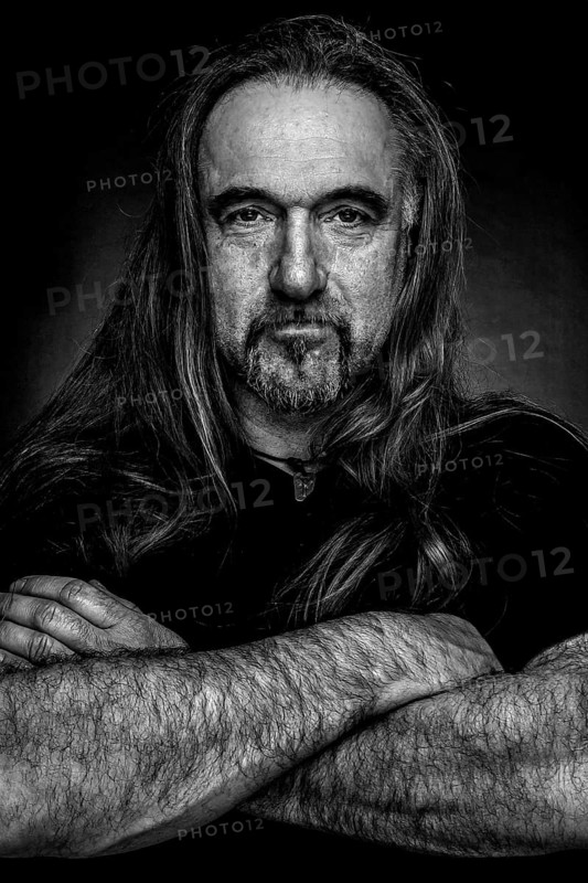 Man with long hair and hand with folded arms