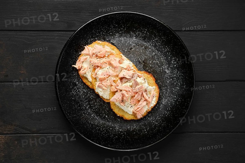 Top view of fried potato patties with greek yogurt and salmon on a plate