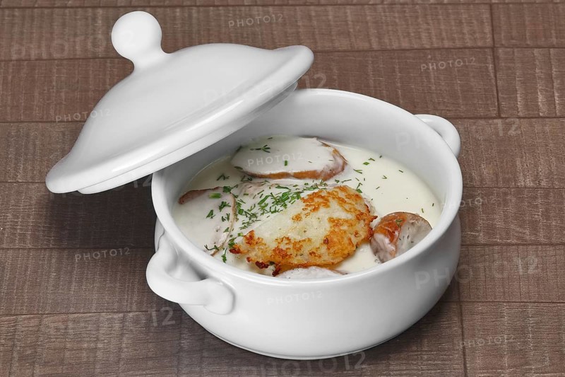 White bowl with machanka and potato pancakes on wooden table