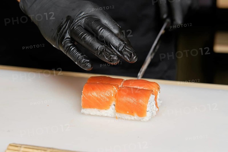 Chef cuts salmon rolls with knife