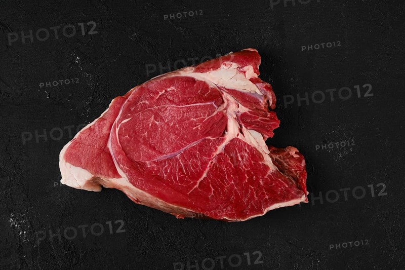 Overhead view of raw top round roast beef steak on dark background