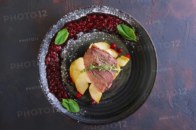 Top view of duck breast with apple and currant sauce