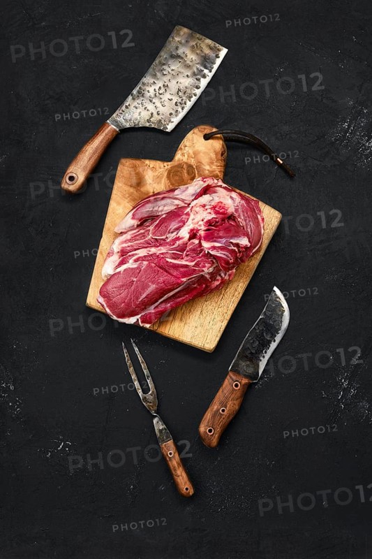 Overhead view of raw lamb shoulder without bone on wooden cutting board