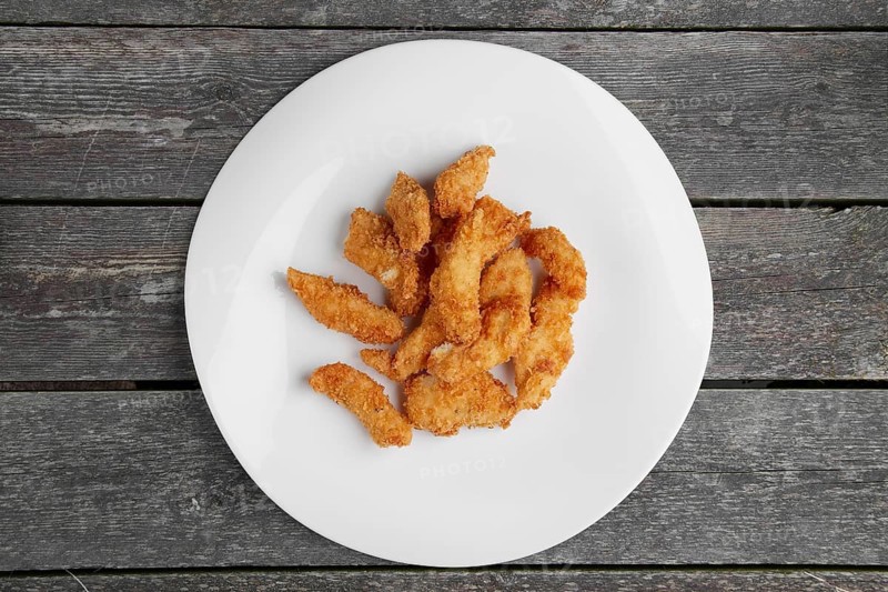 Crisp grilled chicken wings on a white dish on wooden table