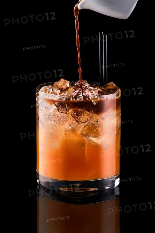 Pouring espresso in glass with tonic and ice isolated on black background