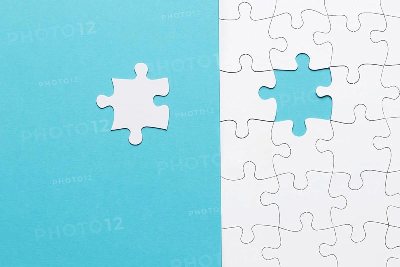 Single white jigsaw puzzle piece blue background