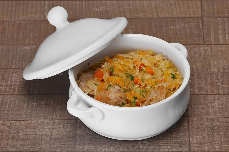 White bowl with homemade sausage and pickled cabbage baked in oven on wooden table