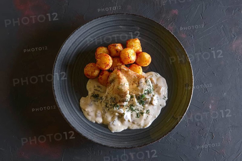 Fried potato balls and white fish fillet with creamy sauce