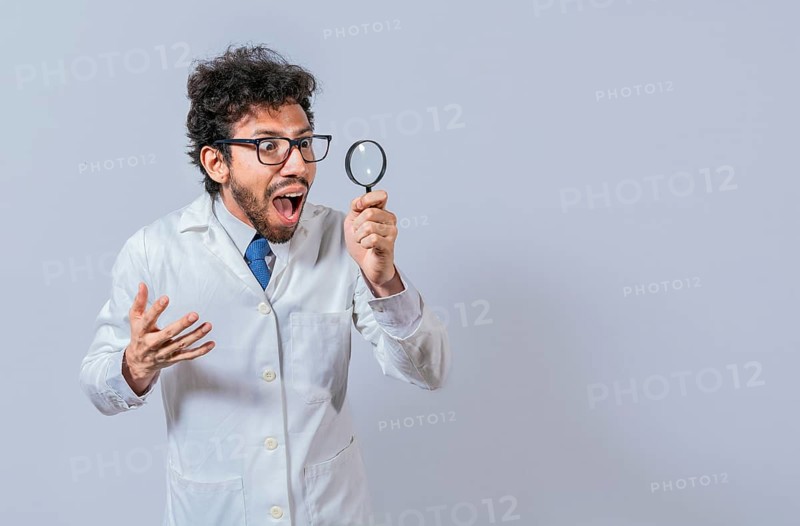 Surprised scientist observing with a magnifying glass to the side. Scientist holding a magnifying glass looking to the side