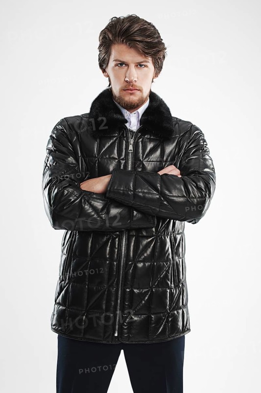 Brutal handsome unshaven man with beard and moustache in waterproof coat with fur collar
