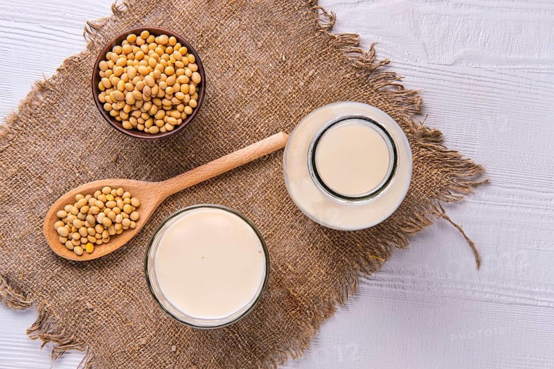 Top view of bottle of soy milk with soybeans on white table