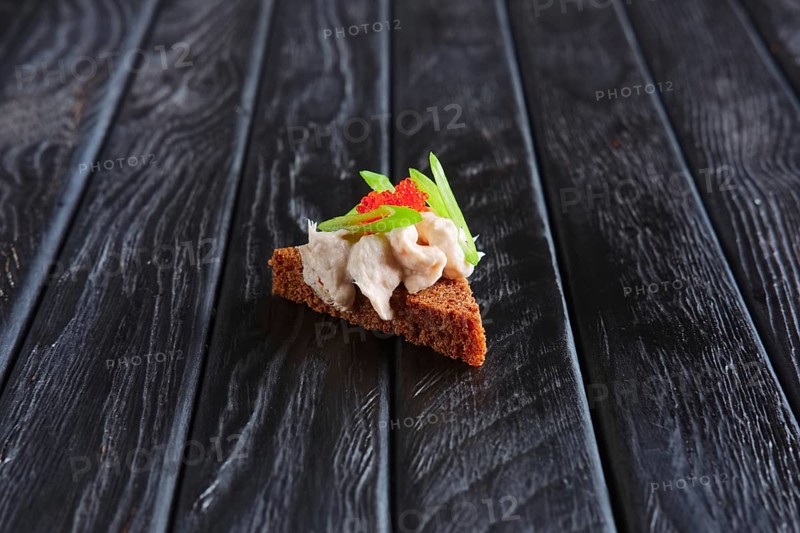 Appetizer for reception. Piece of brown bread with fish pate and green onion