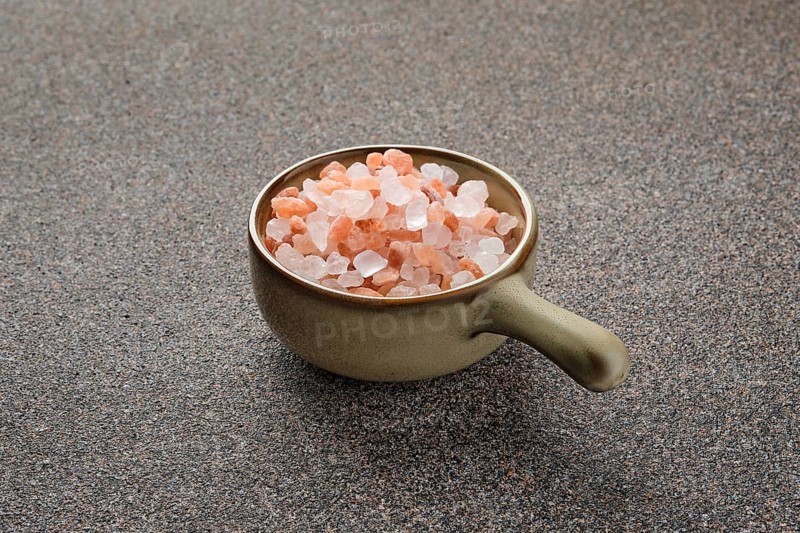 Pink Himalayan salt in a ceramic bowl on stone background