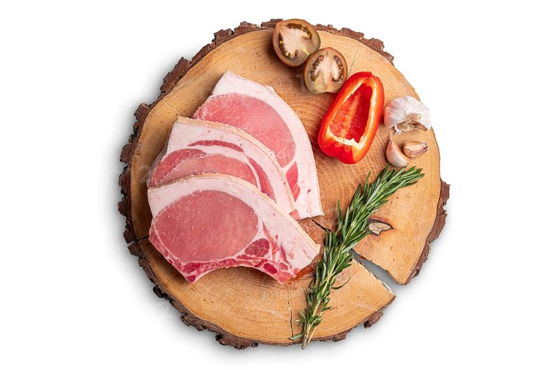 Raw fresh pork fillet steak on the bone on wooden cutting board isolated on white