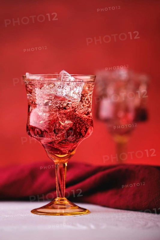 Soft focus photo of cocktail with gin and pomegranate bitter on red background