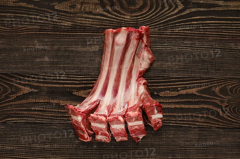 Overhead view of raw fresh doe ribs over dark wooden background