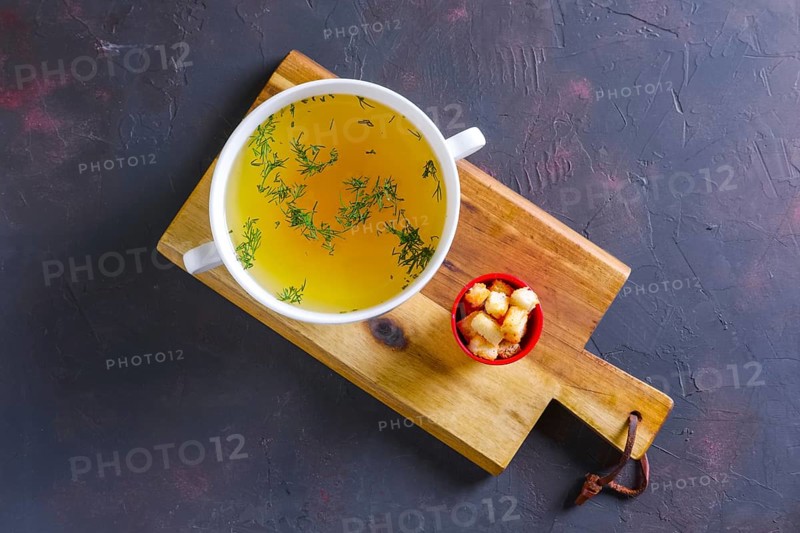 Plate with clear soup and pieces of white bread crouton