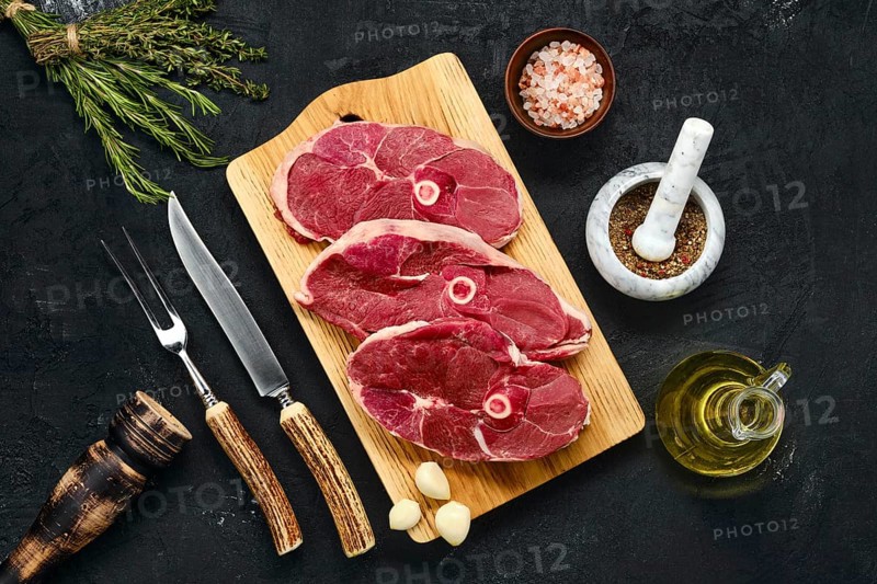 Overhead view of three lamb steak swith spice and knife and fork with horn handle