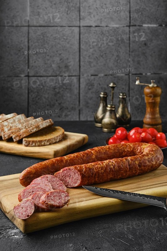 Smoked beef sausage rings on wooden cutting board on kitchen table