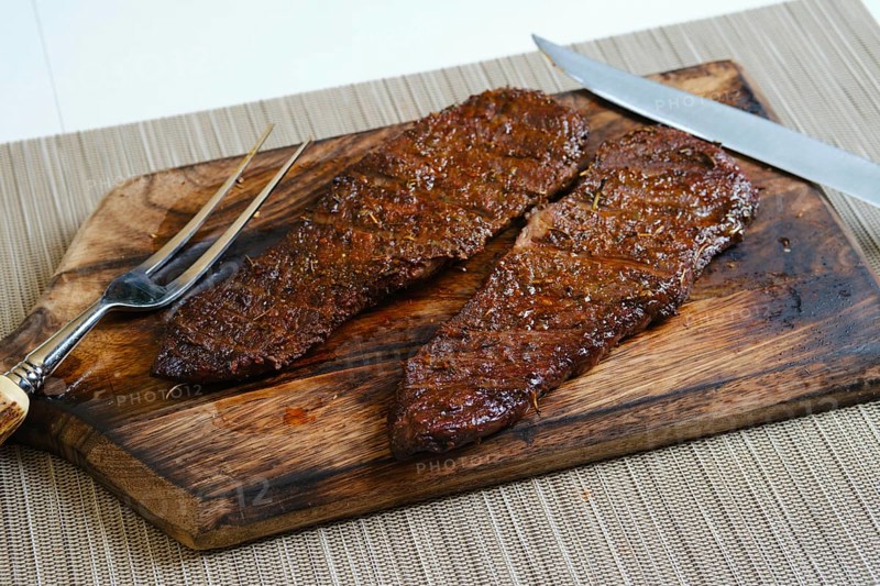 Juicy grilled top blade beefsteak on wooden cutting board