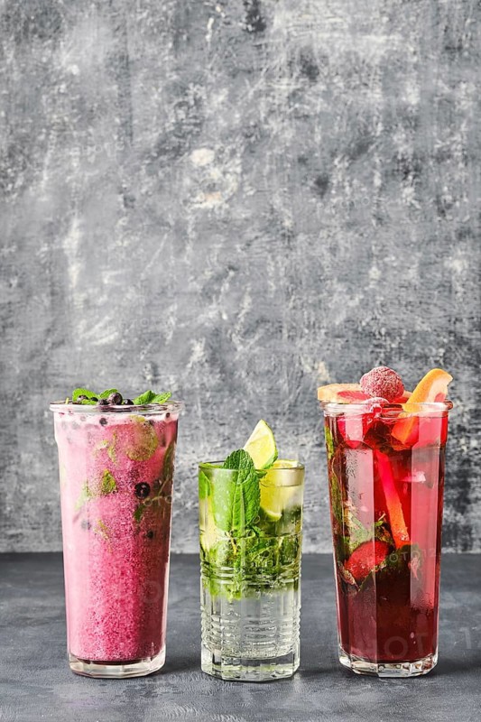 Three glasses with fruit refreshing drink on gray shabby background