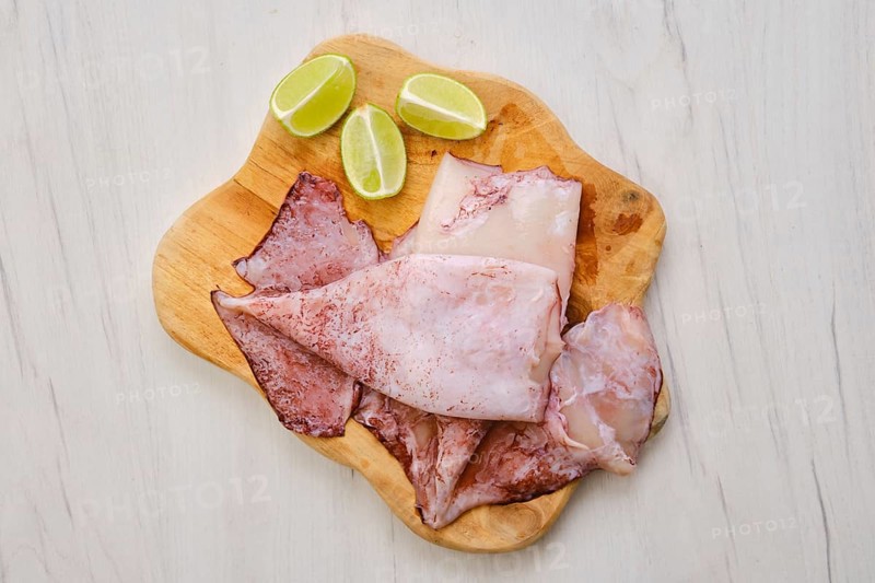 Top view of raw fresh unpeeled squid on wooden cutting board