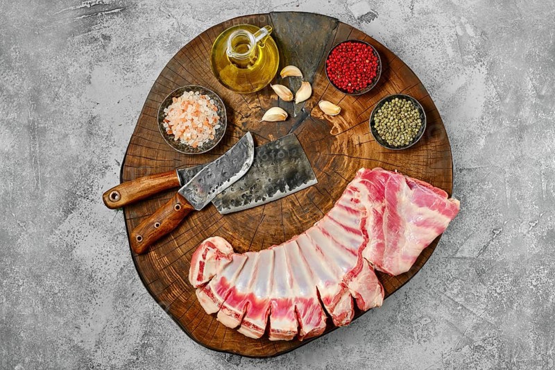 Raw fresh lamb flap ribs with ingredients on wooden log