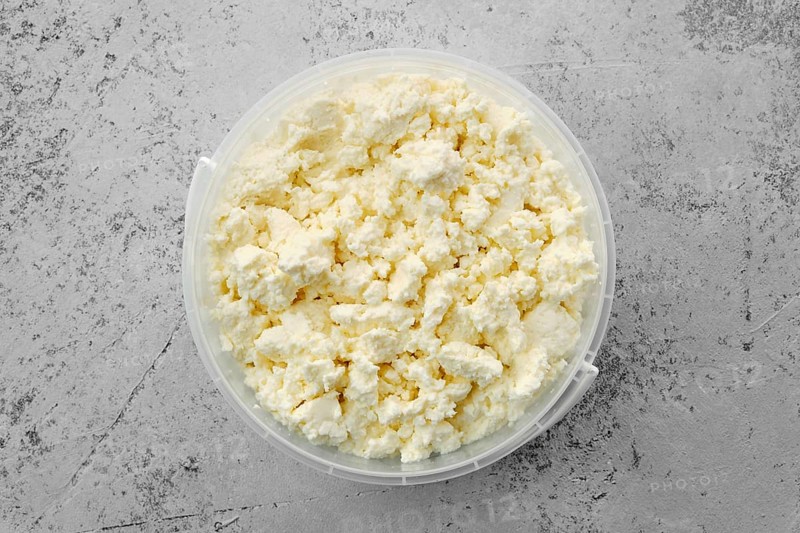 Top view of homemade cottage cheese in plastic bowl