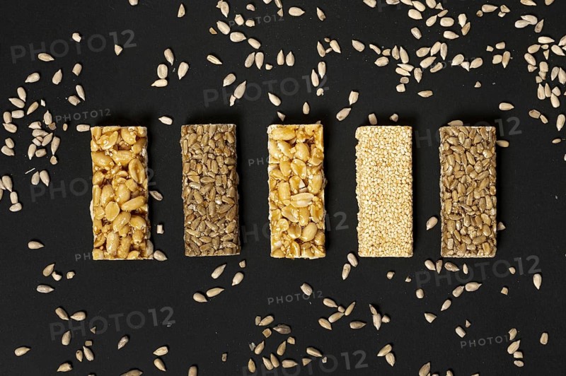 Flat lay cereal bars assortment with sunflower seeds plain background